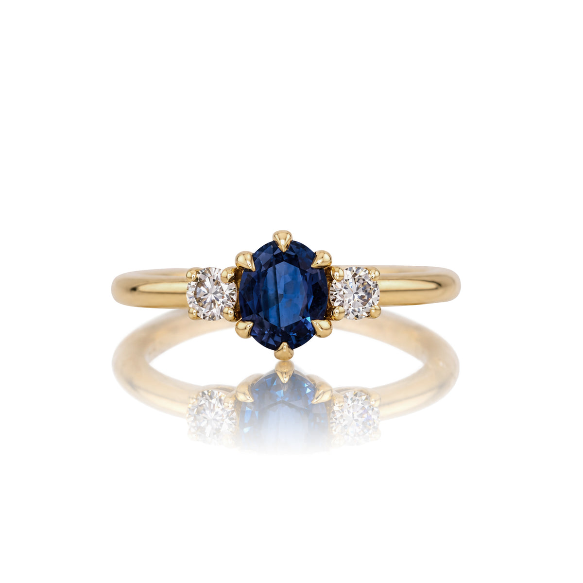 Natural sapphire three stone ring in 14k yellow gold, shown head on against a white background