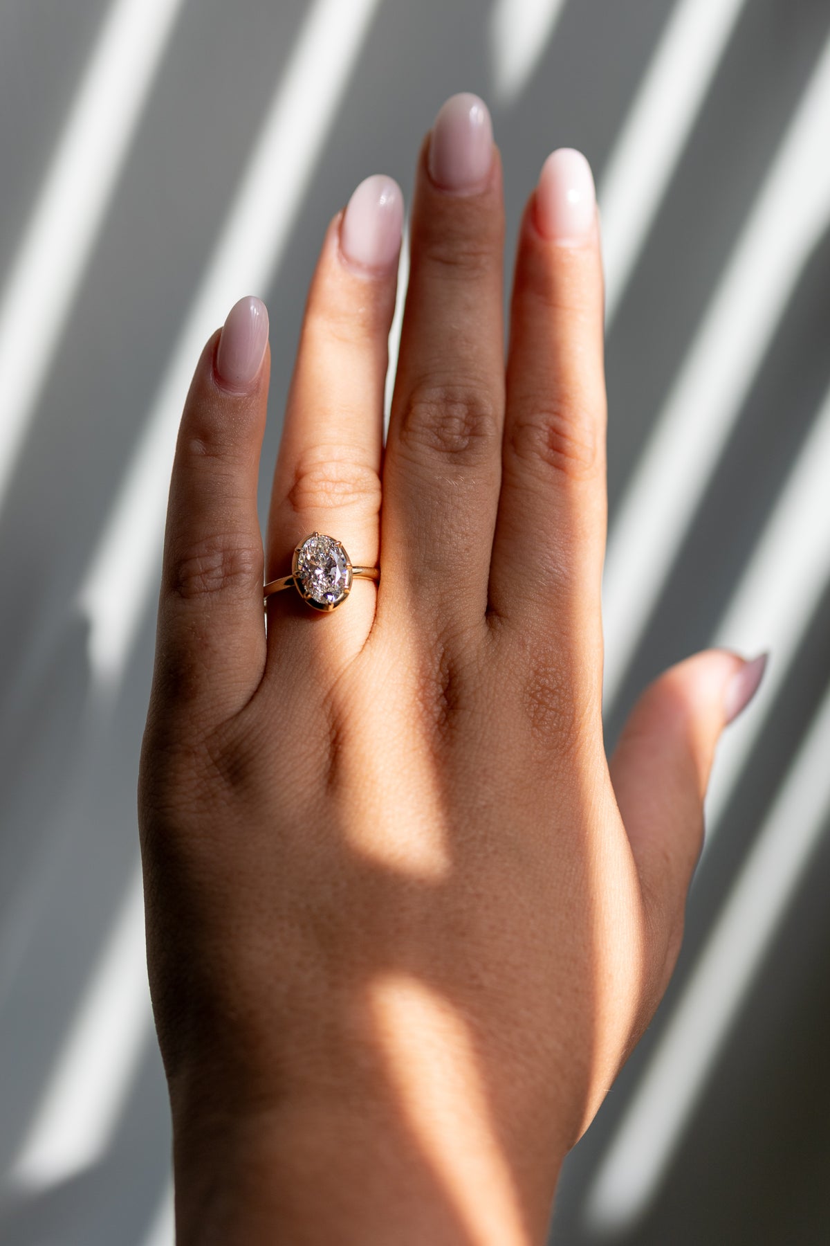 Clara 2.04ct oval collet ring worn on the hand in 14k yellow gold