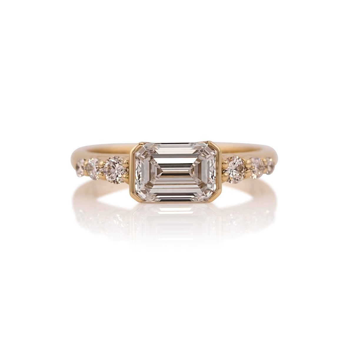 1.31ct emerald cut lab diamond east west ring in 14k yellow gold, shown head on against a white background
