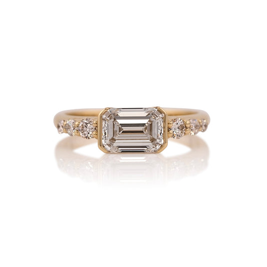 1.31ct emerald cut lab diamond east west ring in 14k yellow gold, shown head on against a white background