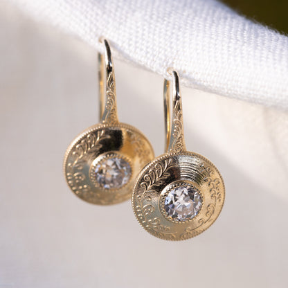 Circular engraved medallion with scrollwork surrounding each old European cut diamond