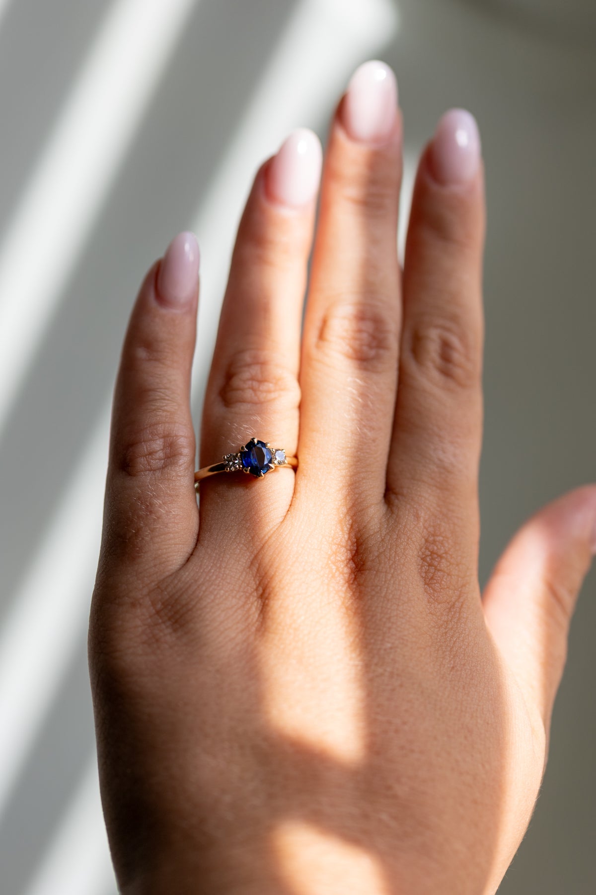 Natural sapphire three stone ring worn on the hand in 14k yellow gold