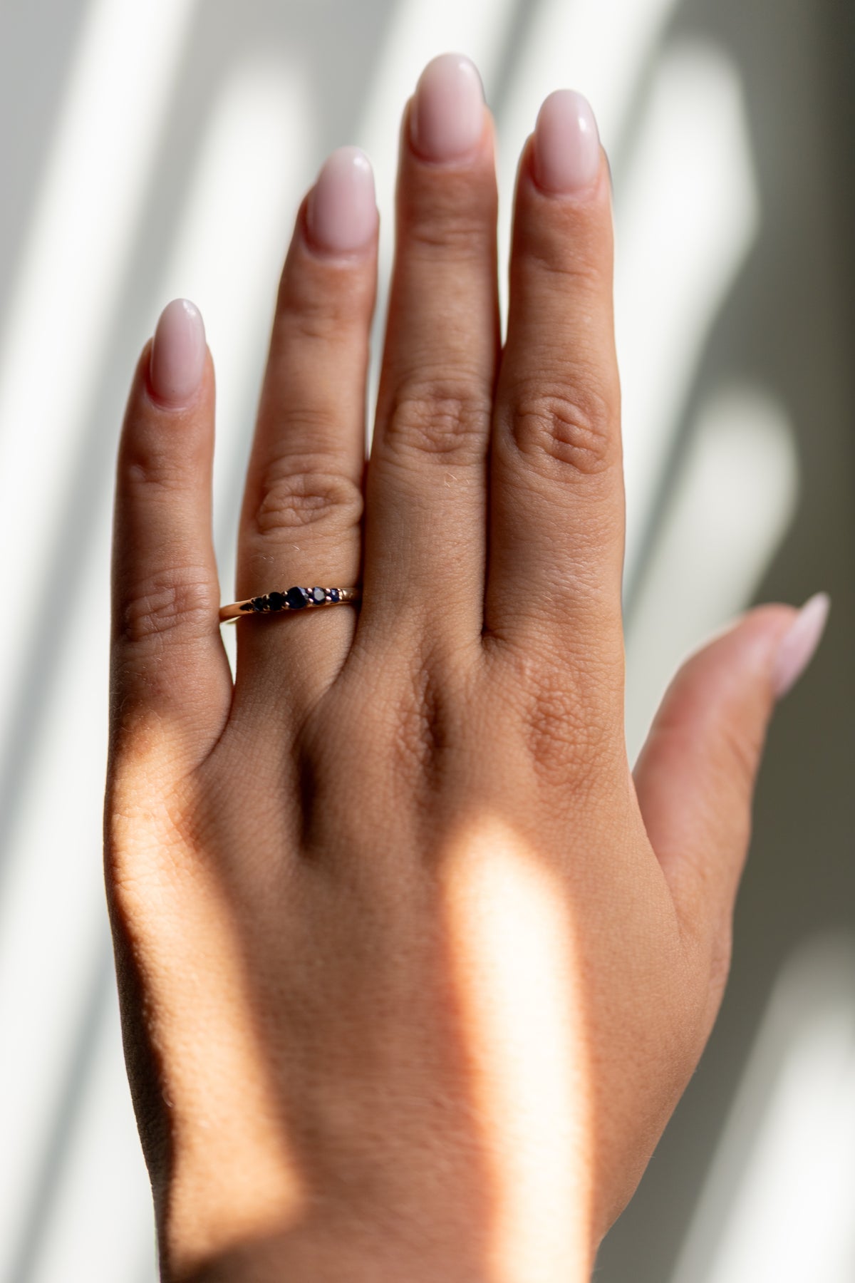 Lab grown sapphire five stone band worn on the hand in 14k yellow gold