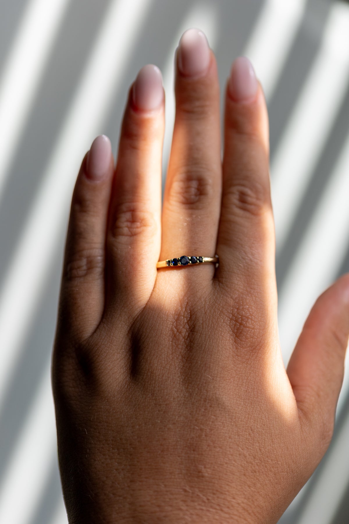 Lab grown sapphire five stone band worn on the hand in 14k yellow gold